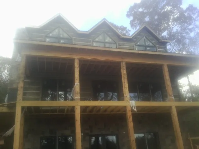 Dormers and porch framing on a large log home under construction — Roof Coating work by our crew in Flovilla