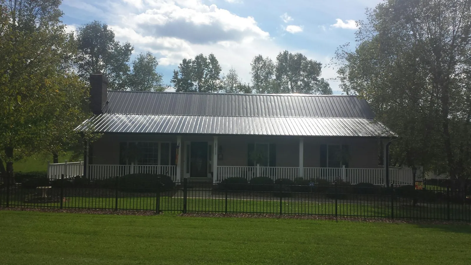Gray metal roof on a brick ranch with a full width front porch — Gutter Guard Installation work by our crew in Flovilla