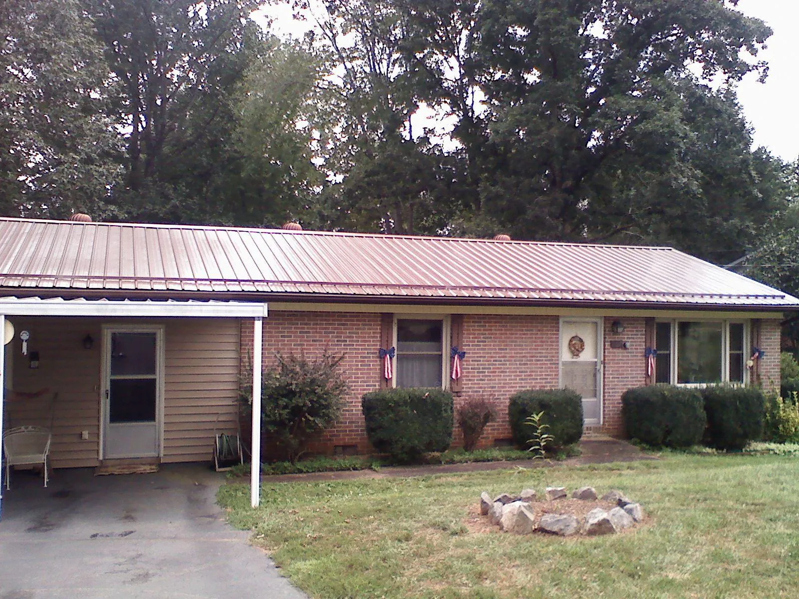 Bronze metal roof and carport on a brick ranch home — Roof Repair work by our crew in Flovilla