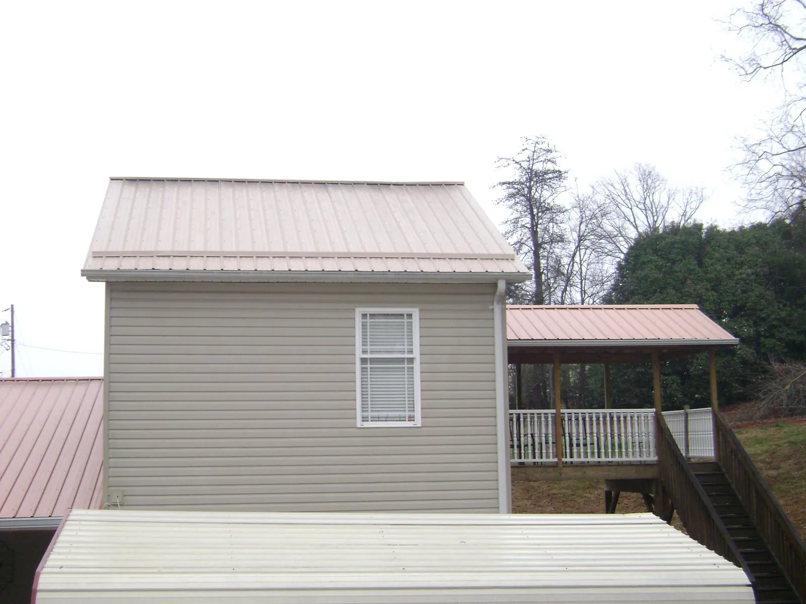 Tan metal roofs on a two story addition and attached porch, from a Roof Replacement job in Flovilla