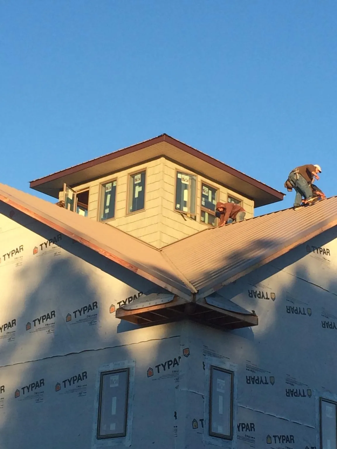 Roofers working around a rooftop cupola on a new metal roof at sunset — Roof Waterproofing in Flovilla by Roofing Brothers